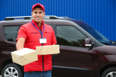 Courier with packages near car outdoors, space for text