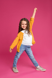 Full length portrait of cute little girl on pink background