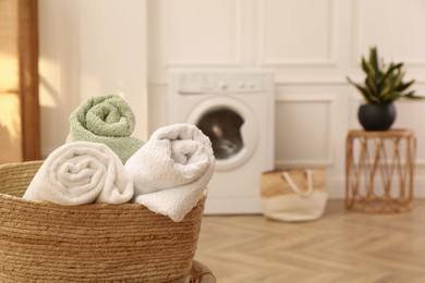 Basket with clean rolled towels on stool in laundry room. Space for text