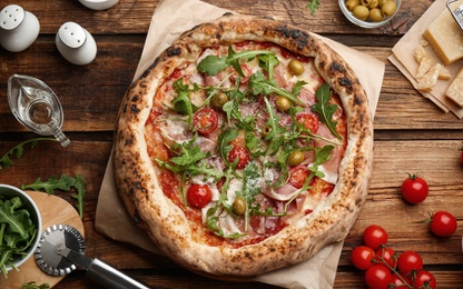 Tasty pizza with meat and arugula on wooden table, flat lay