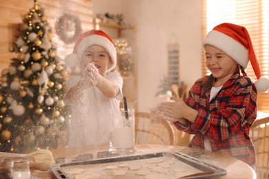 Cute little children having fun while making delicious Christmas cookies at home