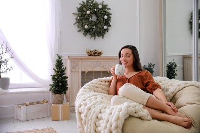 Photo of Woman with hot drink resting in comfortable papasan chair at home. Space for text