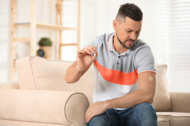 Emotional man with nicotine patch and cigarette at home