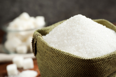 Photo of Granulated sugar in sack on table, closeup
