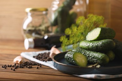 Photo of Fresh cucumbers and other ingredients prepared for canning on wooden table, closeup. Space for text