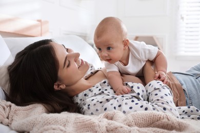 Mother with her cute baby on bed at home