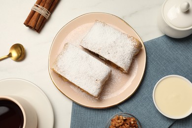 Photo of Delicious strudel with powdered sugar served on white marble table, flat lay