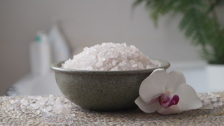 Bowl with bath salt and flower on wicker mat indoors, closeup