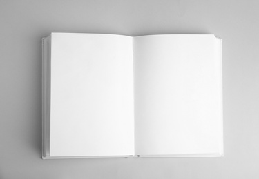 Open book with blank pages on grey background, top view