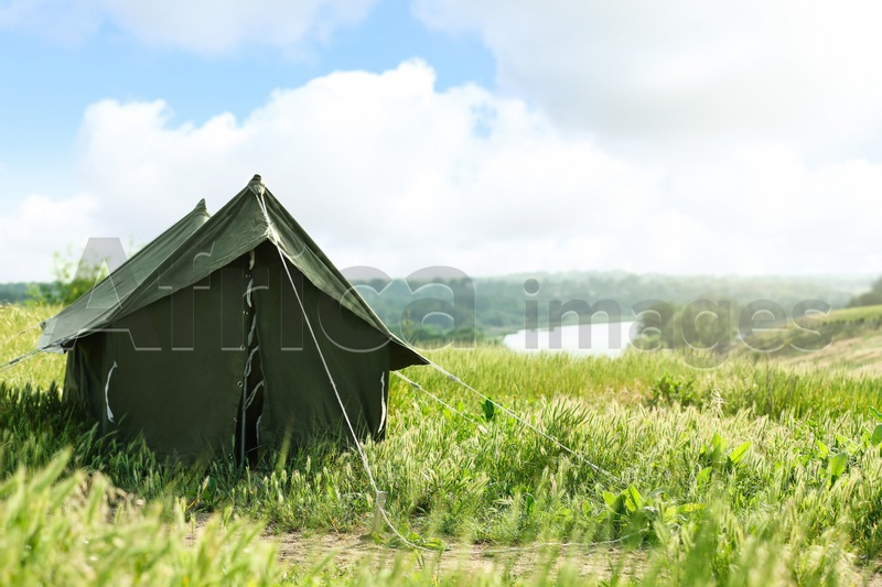 Camping tent in green field on sunny day. Space for text