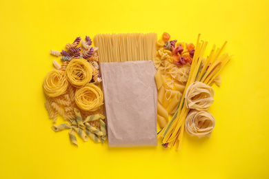 Different types of pasta on yellow background, flat lay