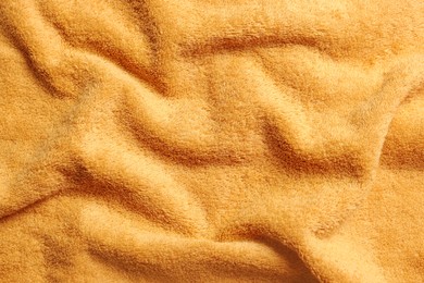 Soft crumpled orange towel as background, top view