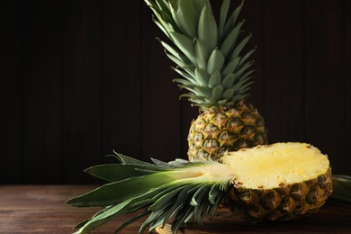 Photo of Whole and cut pineapples on wooden table