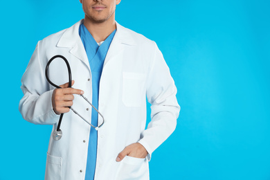Doctor with stethoscope on blue background, closeup. Space for text