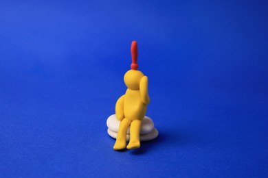 Photo of Human figure made of yellow plasticine with exclamation mark as solution idea on blue background