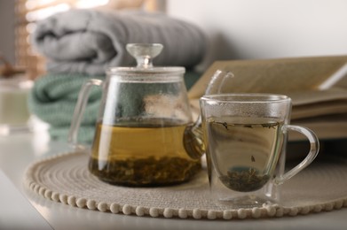 Glass teapot and cup of hot tea on table in room. Cozy home atmosphere