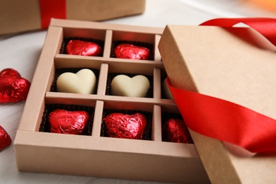 Tasty heart shaped chocolate candies on white wooden table, closeup. Happy Valentine's day