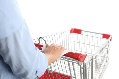 Woman holding shopping cart handle with tissue paper on white background, closeup