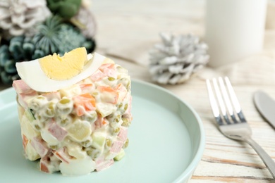 Traditional russian salad Olivier served on white wooden table, closeup