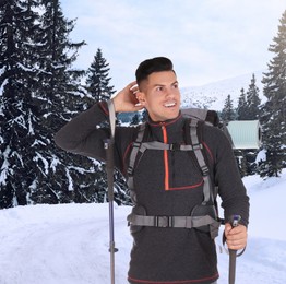 Man with backpack and trekking poles in snowy mountains