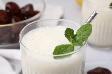 Photo of Glass of delicious date smoothie with mint on table, closeup