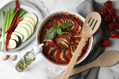 Photo of Delicious ratatouille and ingredients on white marble table, flat lay