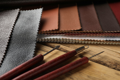 Leather samples and tools on wooden table, closeup