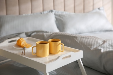 Soft blanket and tray with breakfast on bed, closeup