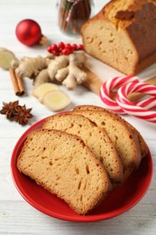 Photo of Slices of delicious gingerbread cake, ingredients and candy canes on white wooden table