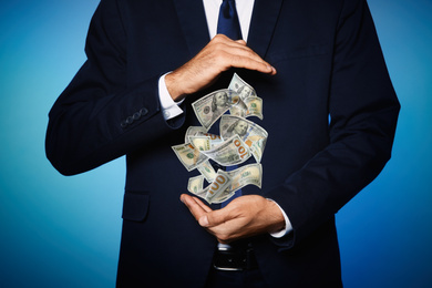 Businessman with money on blue background, closeup. Currency exchange