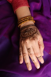 Woman with beautiful henna tattoo on hand, closeup. Traditional mehndi
