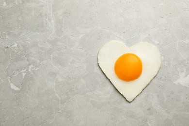 Tasty fried egg in shape of heart on marble table, top view. Space for text