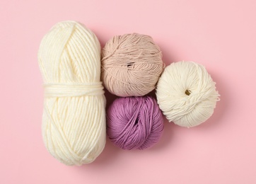 Soft woolen yarns on pink background, flat lay