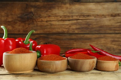 Bowls of paprika with peppers on wooden table
