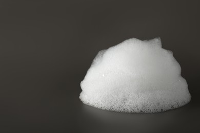 Drop of fluffy bath foam on grey background, closeup. Space for text