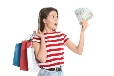 Emotional young woman with money and shopping bags on white background