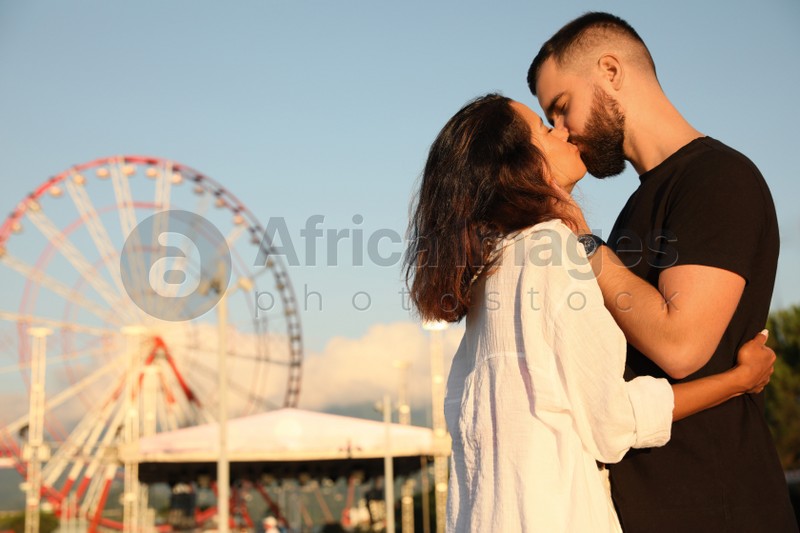 Happy young couple kissing in amusement park