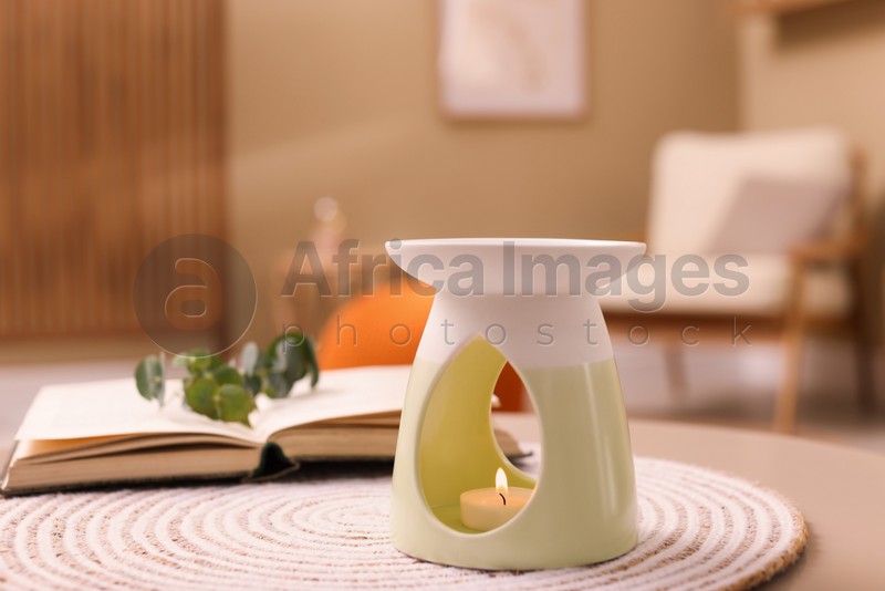 Stylish aroma lamp with small candle on table indoors