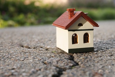 Wooden house model on cracked asphalt. Earthquake disaster