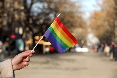 Woman holding bright LGBT flag on city street, closeup