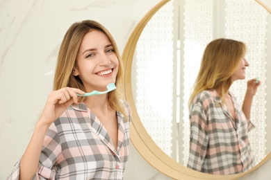 Woman brushing teeth near mirror in bathroom