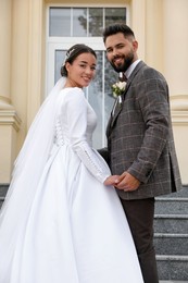 Young bride and groom on stairs outdoors. Wedding couple