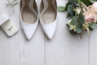 Flat lay composition with wedding high heel shoes on white wooden floor. Space for text