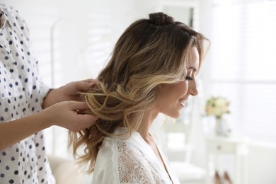 Professional stylist making wedding hairstyle for bride in salon