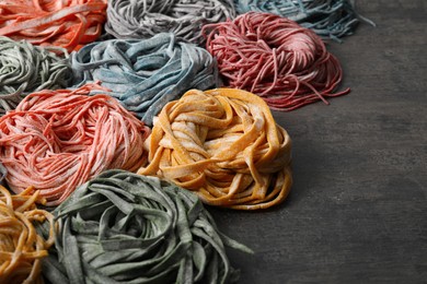 Photo of Rolled pasta painted with food colorings on dark grey table, closeup. Space for text