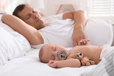 Photo of Father with his cute baby sleeping in bed at home