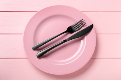 Photo of Ceramic plate with cutlery on pink wooden table, top view