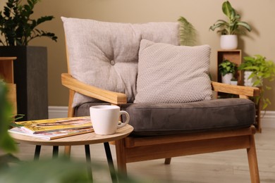 Comfortable armchair near wooden coffee table in room. Interior design