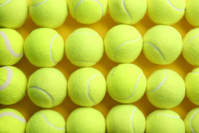 Tennis balls on yellow background, flat lay. Sports  equipment