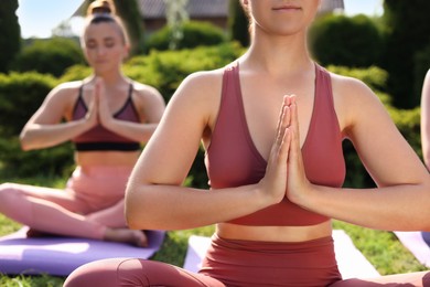 Young women practicing yoga on mats outdoors, closeup